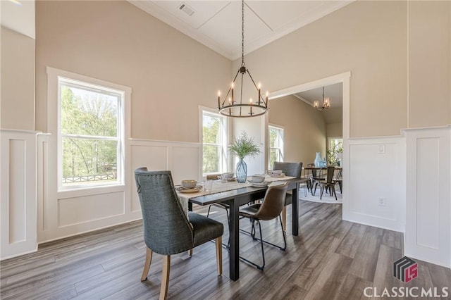 dining room with a wealth of natural light, a decorative wall, a notable chandelier, and visible vents