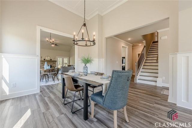 dining room with stairs, a towering ceiling, a notable chandelier, and wood finished floors
