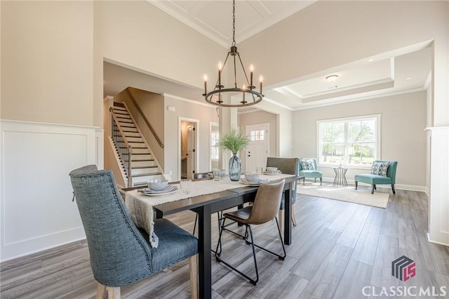dining area with a chandelier, crown molding, wood finished floors, and stairs