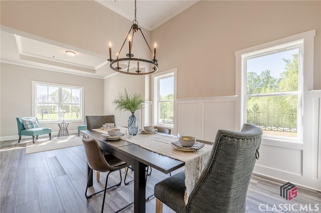 dining area featuring a decorative wall, a chandelier, crown molding, wainscoting, and wood finished floors