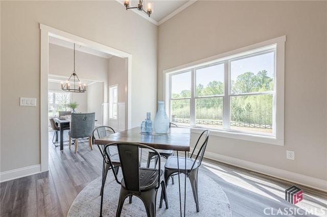 dining space with baseboards, an inviting chandelier, wood finished floors, and a healthy amount of sunlight