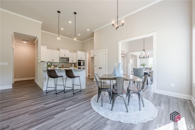 dining area featuring baseboards, a high ceiling, an inviting chandelier, and wood finished floors