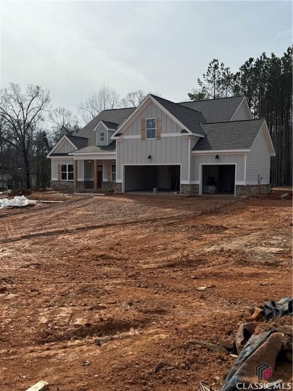 craftsman house featuring stone siding, a shingled roof, and board and batten siding