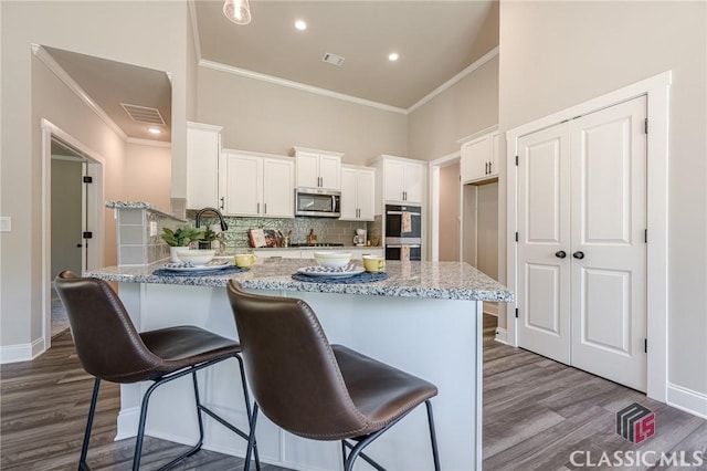 kitchen with a peninsula, dark wood-style flooring, visible vents, and stainless steel appliances