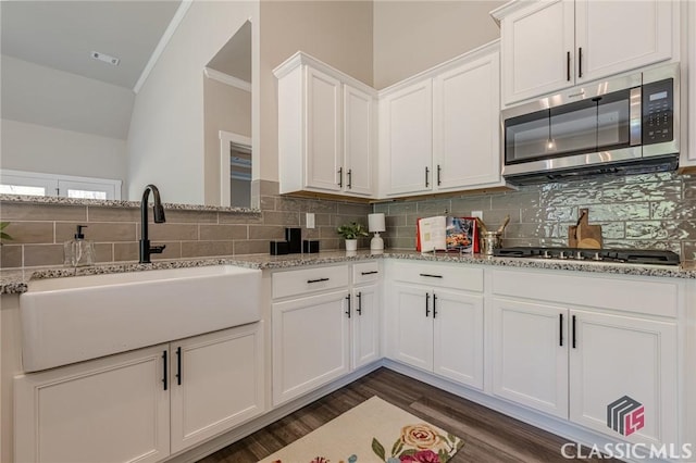 kitchen with a sink, backsplash, white cabinetry, and stainless steel appliances