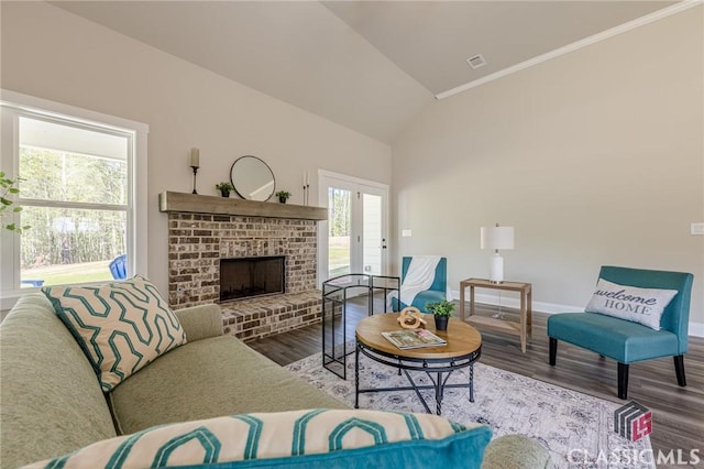 living room featuring visible vents, wood finished floors, a brick fireplace, lofted ceiling, and baseboards