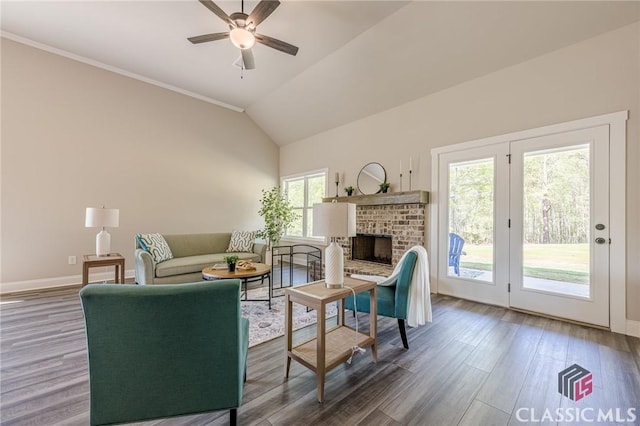 living room featuring wood finished floors, a fireplace, a ceiling fan, and vaulted ceiling