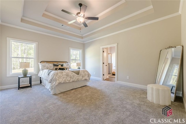 carpeted bedroom with visible vents, baseboards, ornamental molding, and a raised ceiling
