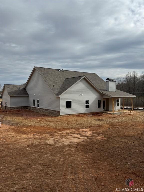 view of property exterior featuring a shingled roof and a chimney