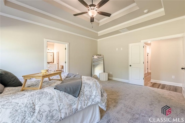 carpeted bedroom featuring visible vents, baseboards, ornamental molding, a ceiling fan, and a tray ceiling