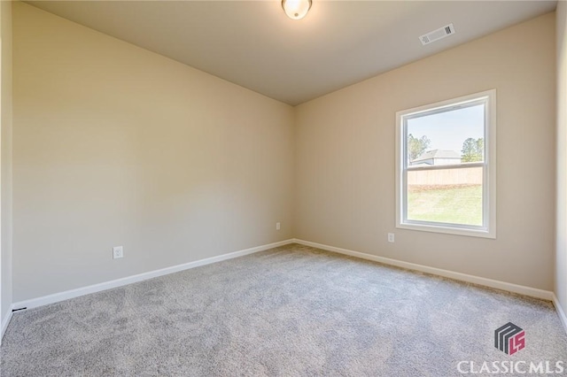 unfurnished room with carpet, visible vents, and baseboards