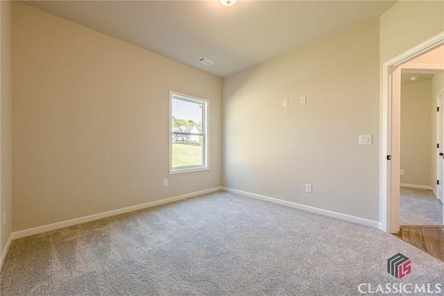 carpeted spare room featuring visible vents and baseboards