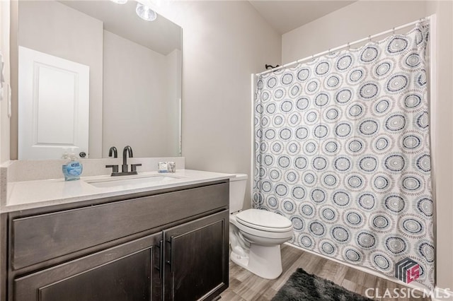 bathroom featuring toilet, curtained shower, wood finished floors, and vanity