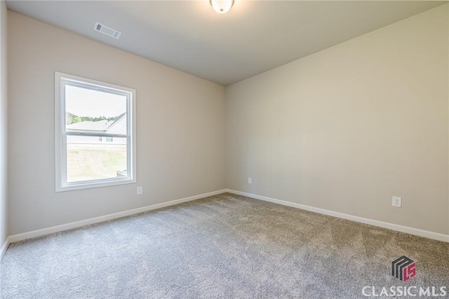 spare room featuring carpet flooring, baseboards, and visible vents