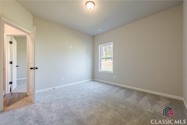 unfurnished room with carpet flooring, baseboards, and visible vents