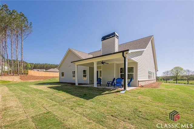 back of house featuring a yard, ceiling fan, a patio, and a chimney