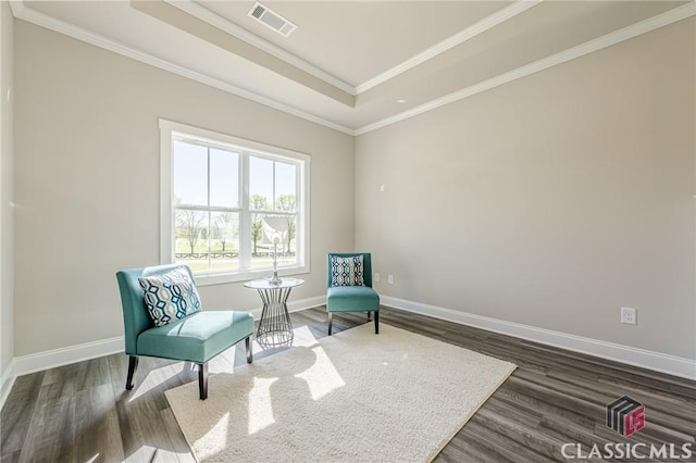 sitting room with visible vents, baseboards, ornamental molding, a tray ceiling, and wood finished floors