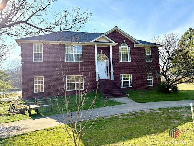 bi-level home featuring a front lawn and brick siding