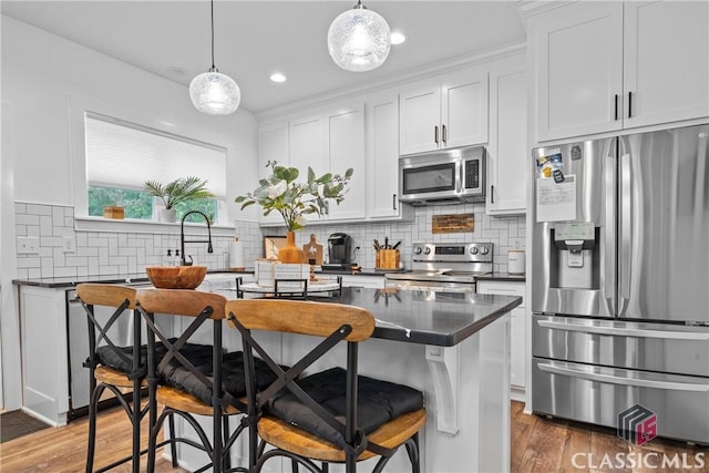 kitchen with appliances with stainless steel finishes, dark countertops, backsplash, and light wood-style flooring