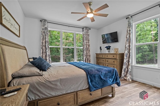 bedroom with baseboards, multiple windows, light wood-style flooring, and a ceiling fan