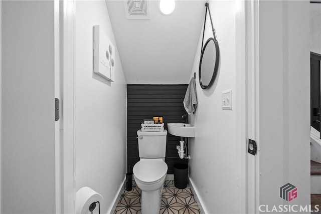 half bath with tile patterned flooring, baseboards, and toilet