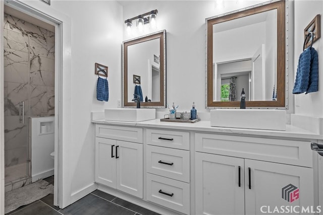 bathroom with tile patterned floors, a sink, a marble finish shower, and double vanity