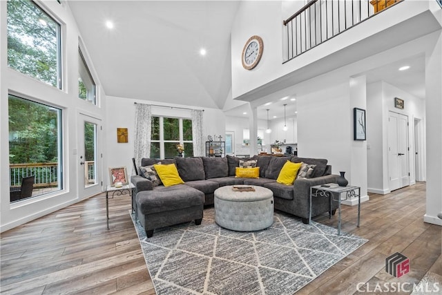 living room with wood-type flooring, a high ceiling, baseboards, and recessed lighting