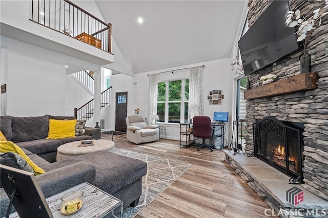 living room featuring stairs, a fireplace, a towering ceiling, and wood finished floors