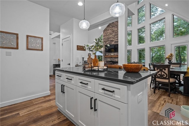 kitchen with dark wood-style floors, a fireplace, dark countertops, a high ceiling, and white cabinetry