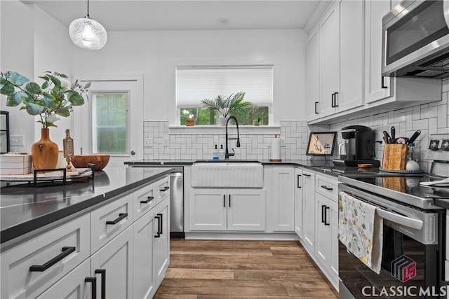 kitchen featuring dark wood-type flooring, a sink, white cabinetry, appliances with stainless steel finishes, and dark countertops