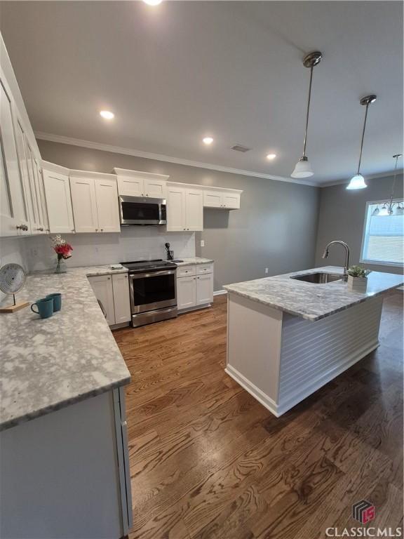 kitchen with stainless steel appliances, dark wood-type flooring, ornamental molding, white cabinetry, and a sink