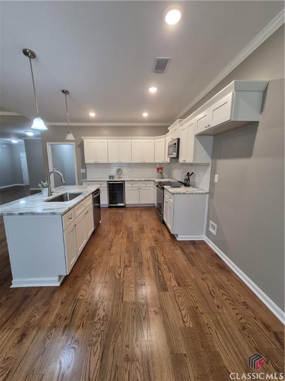 kitchen featuring visible vents, a sink, wine cooler, appliances with stainless steel finishes, and crown molding