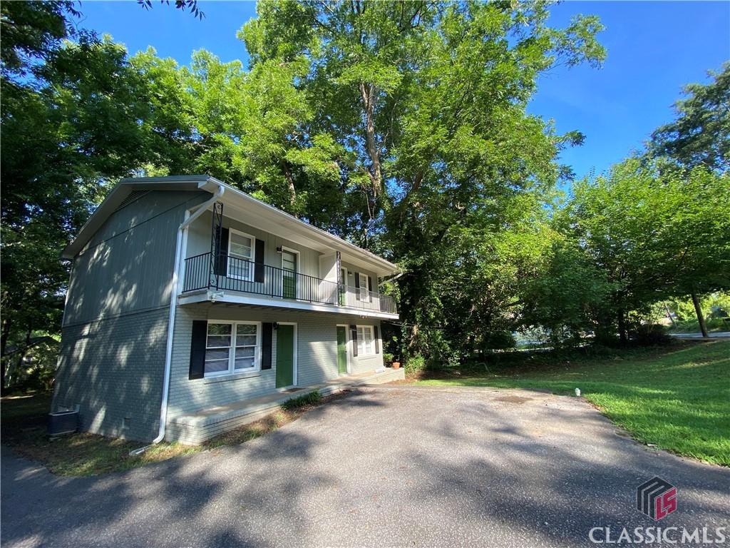 view of front property featuring a balcony, a front yard, and brick siding