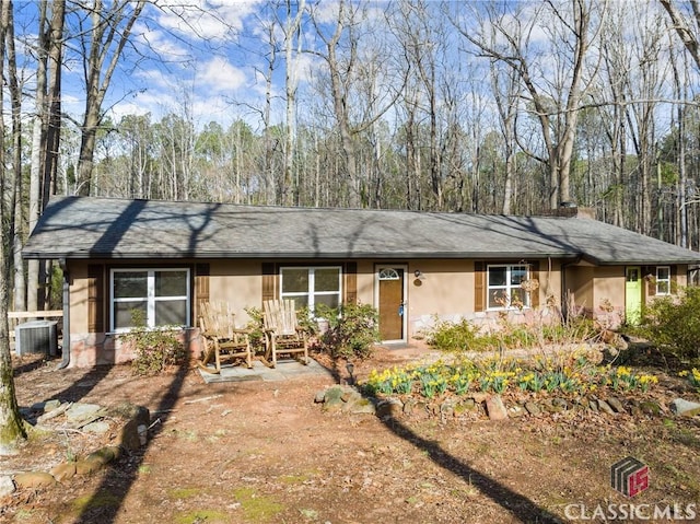 ranch-style home with a chimney, cooling unit, and stucco siding