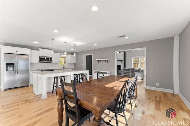 dining room featuring light wood-style floors, visible vents, baseboards, and recessed lighting