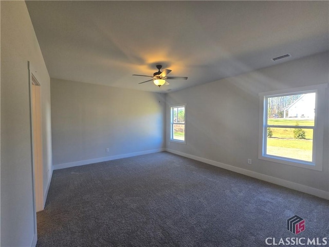 carpeted spare room featuring a ceiling fan, visible vents, and baseboards