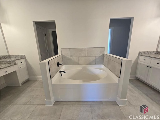 full bath with a garden tub, vanity, baseboards, and tile patterned floors