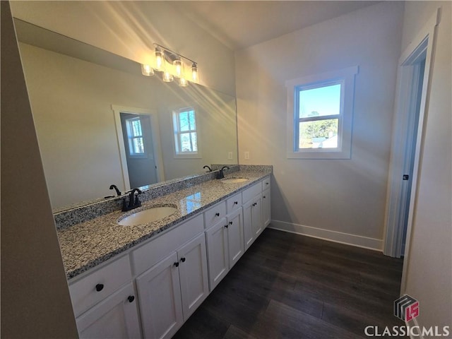 bathroom featuring double vanity, baseboards, a sink, and wood finished floors