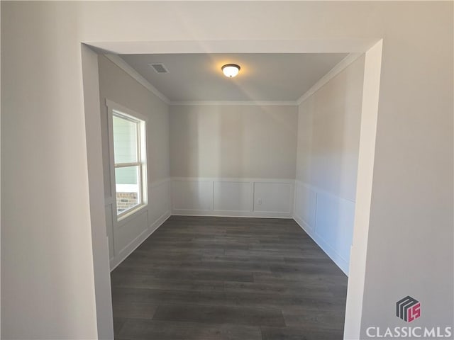 unfurnished room with crown molding, a wainscoted wall, visible vents, and dark wood finished floors