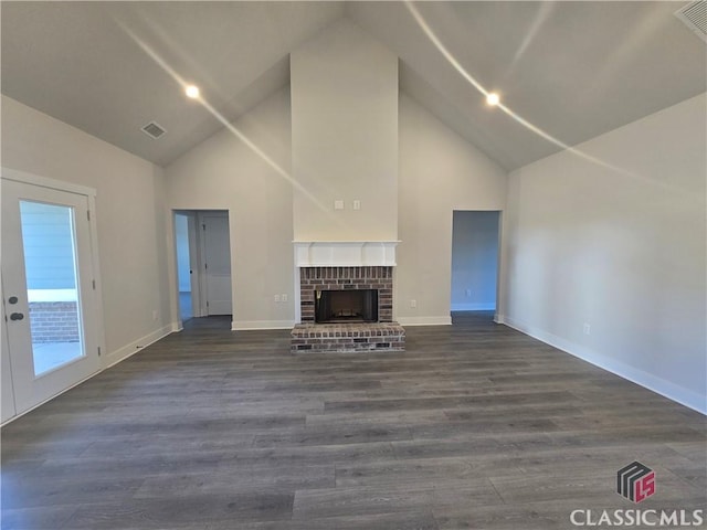 unfurnished living room with a fireplace, dark wood finished floors, visible vents, and baseboards