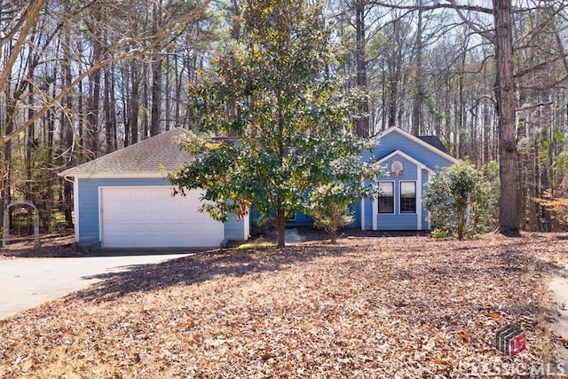 view of front of house featuring a garage, concrete driveway, and roof with shingles