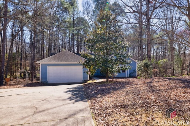 single story home featuring a garage and roof with shingles