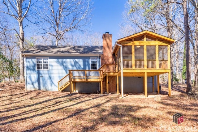 back of property with stairway, a chimney, a wooden deck, and a sunroom