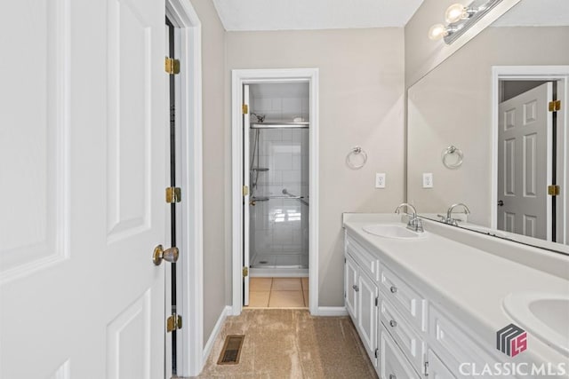 full bathroom with a sink, visible vents, baseboards, a tile shower, and double vanity