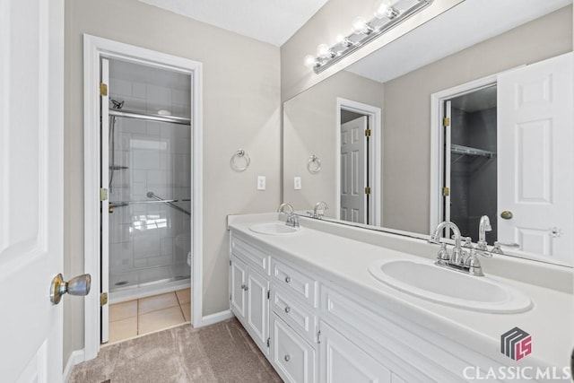 full bath with a stall shower, a sink, baseboards, and double vanity