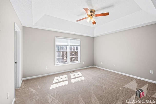 unfurnished room featuring a tray ceiling, carpet flooring, and baseboards