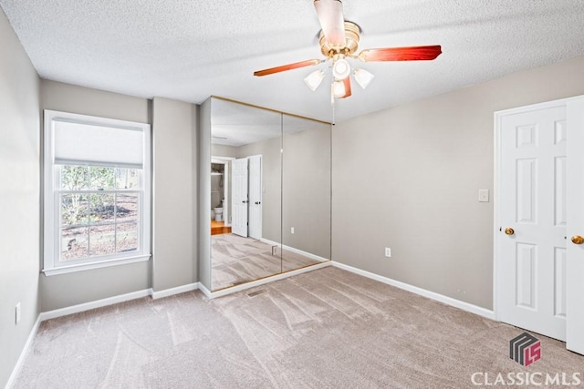 unfurnished bedroom with a textured ceiling, carpet, visible vents, and baseboards