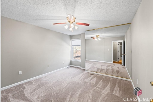 carpeted spare room with a textured ceiling, a ceiling fan, and baseboards