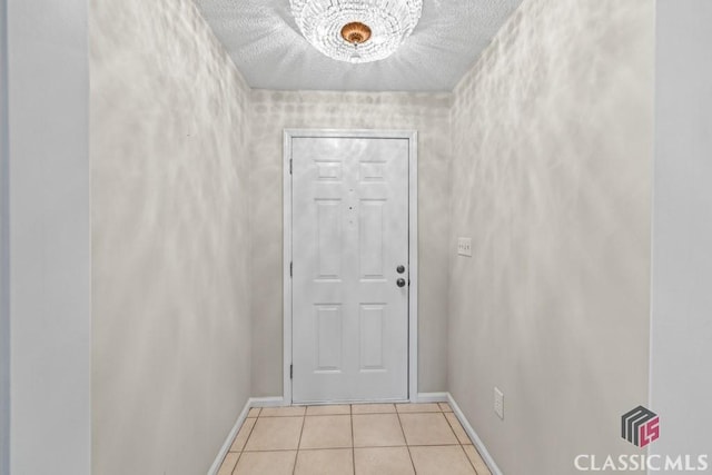 doorway featuring baseboards, a textured ceiling, and tile patterned floors