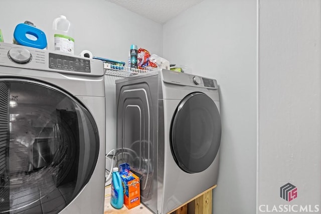 clothes washing area featuring laundry area, a textured ceiling, and washer and dryer